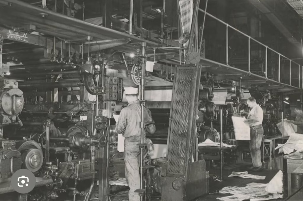 Historic black-and-white photo of press operators working alongside large industrial printing machines in the Philadelphia Inquirer pressroom.